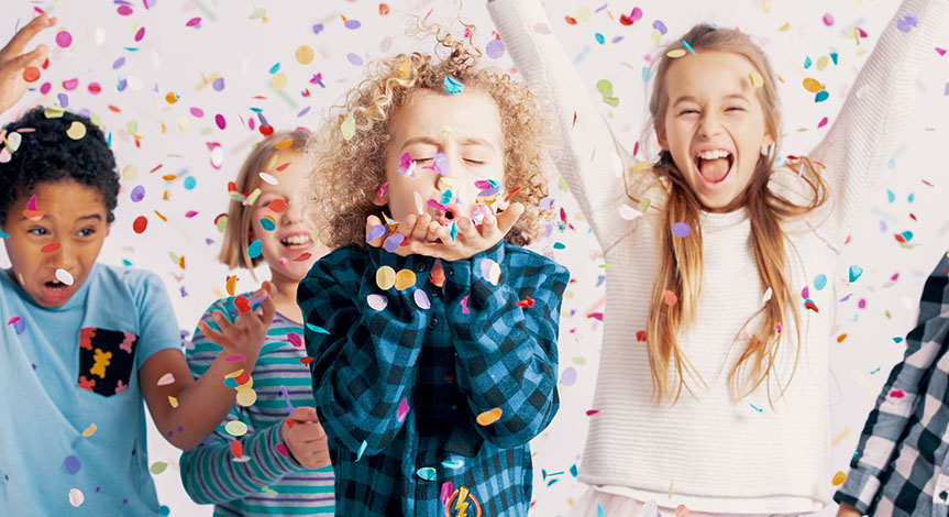 Happy group of kids having fun during birthday party with confetti