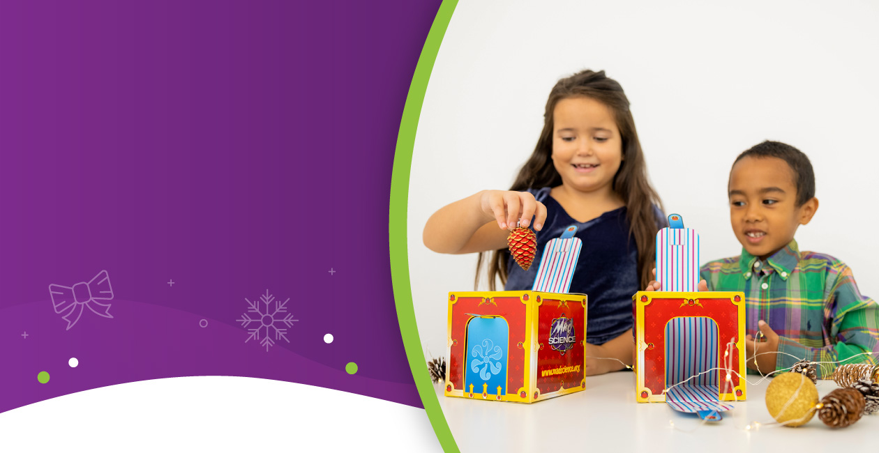 Kids playing with our Curious Cube take-home toy on a table covered with pinecones and Holiday ornaments. 