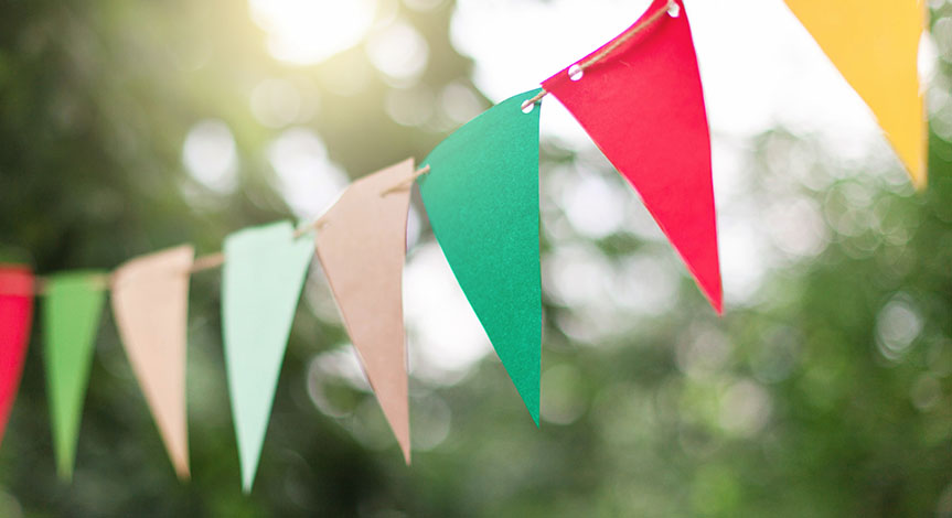 Colorful flags at sunset in garden. Concept of celebration or party. Paper festive decoration outdoor.